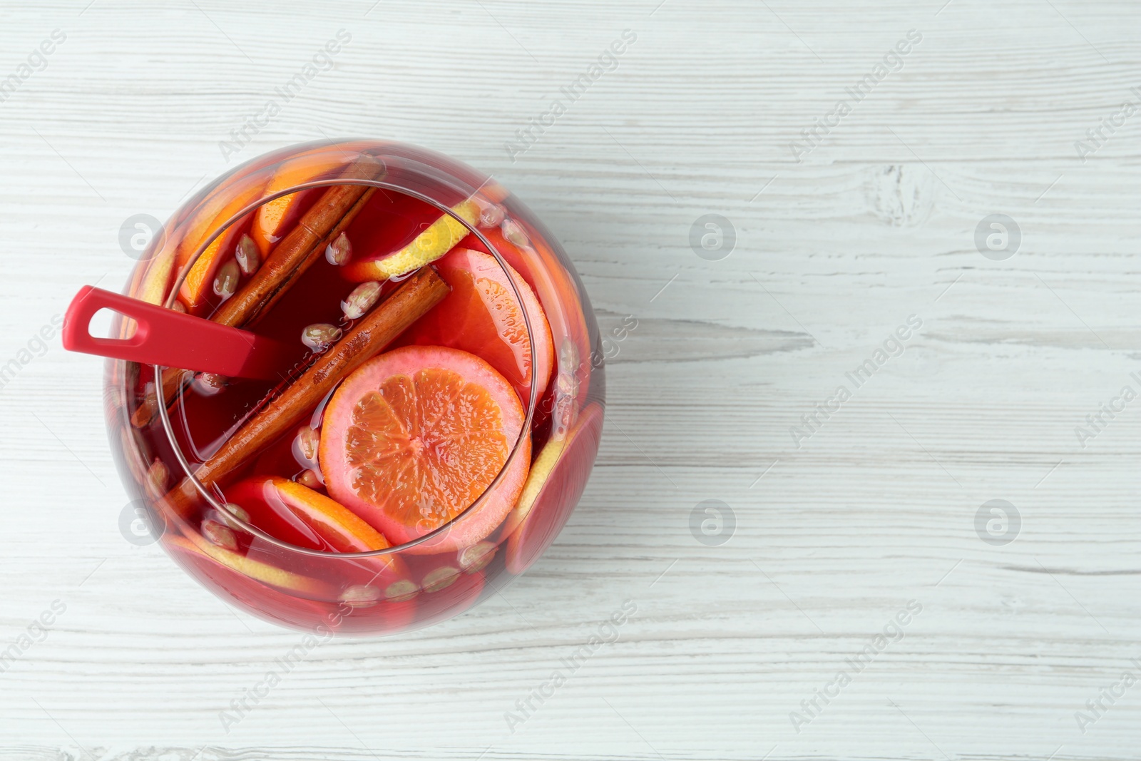 Photo of Glass bowl of aromatic punch drink on white wooden table, top view. Space for text