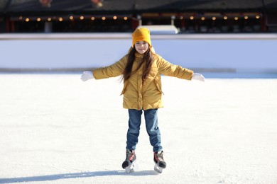 Cute little girl at outdoor ice skating rink