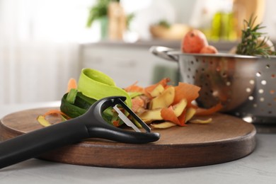 Photo of Peels of fresh vegetables and peeler on light table, closeup