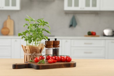 Beautiful potted basil, cherry tomatoes and spices on table in kitchen. Space for text