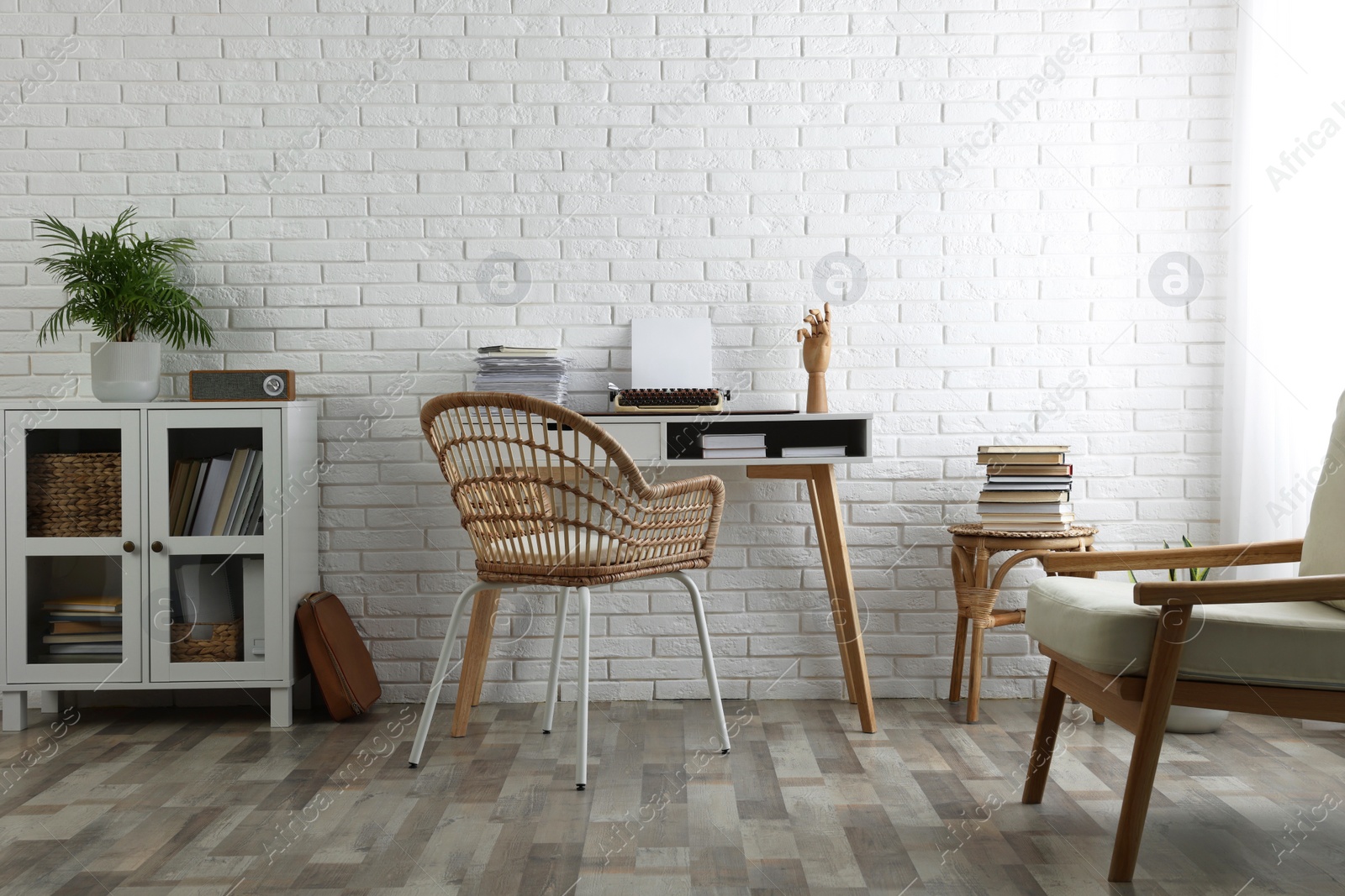 Photo of Comfortable writer's workplace interior with typewriter on desk near white brick wall