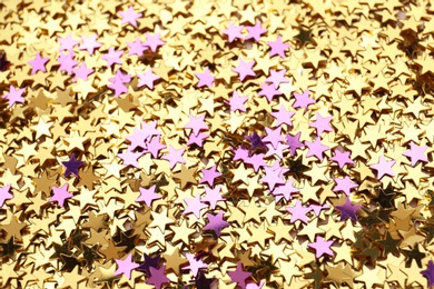 Golden and purple confetti stars as background, closeup. Christmas celebration