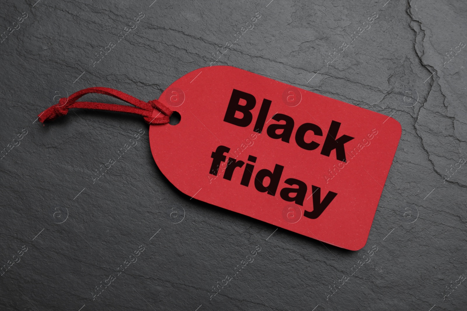 Photo of Red tag on dark stone background, top view. Black Friday sale