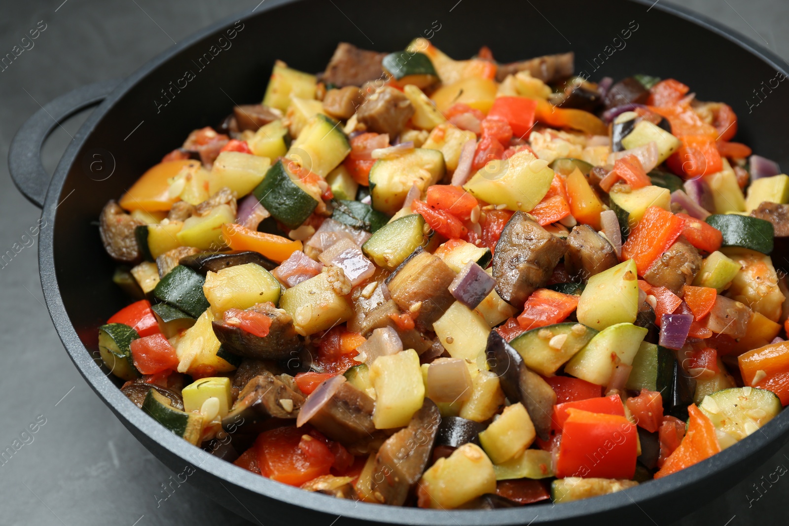 Photo of Delicious ratatouille in baking dish on grey table, closeup