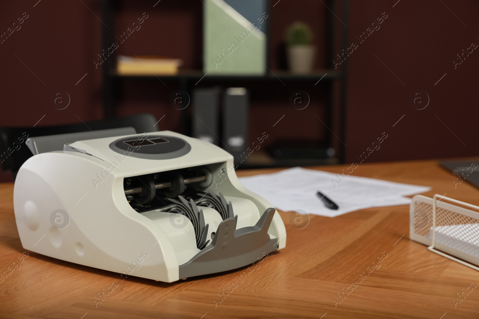 Photo of Modern banknote counter on wooden table indoors