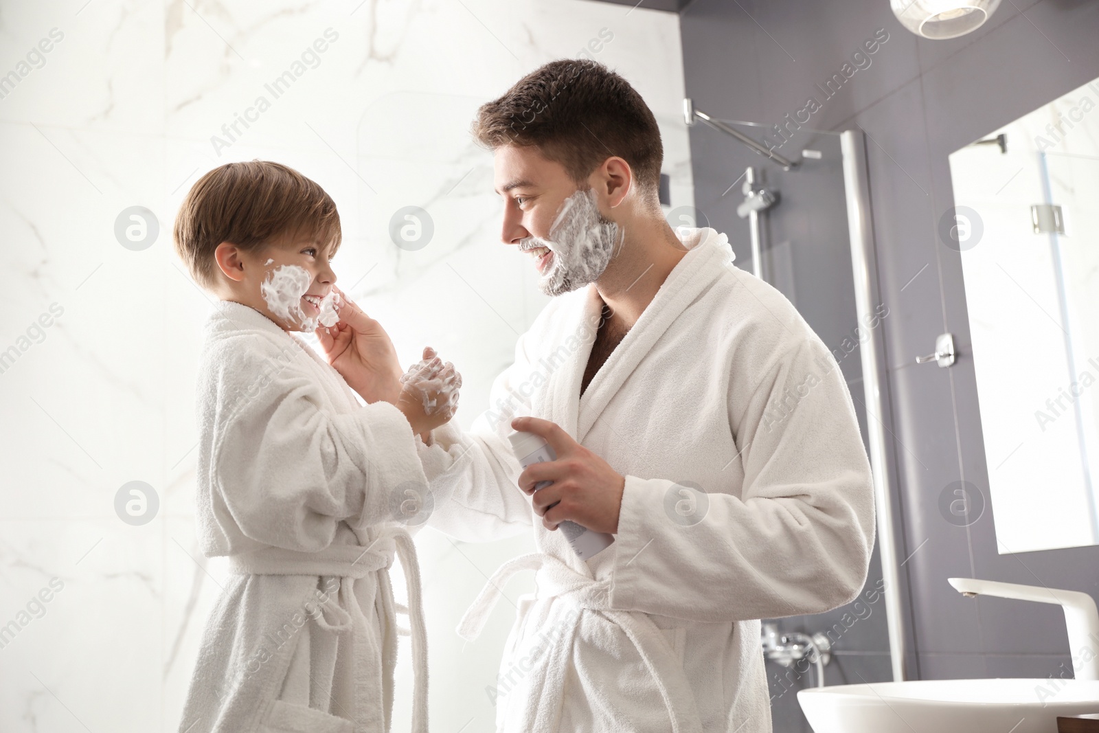 Photo of Dad applying shaving foam onto son's face in bathroom