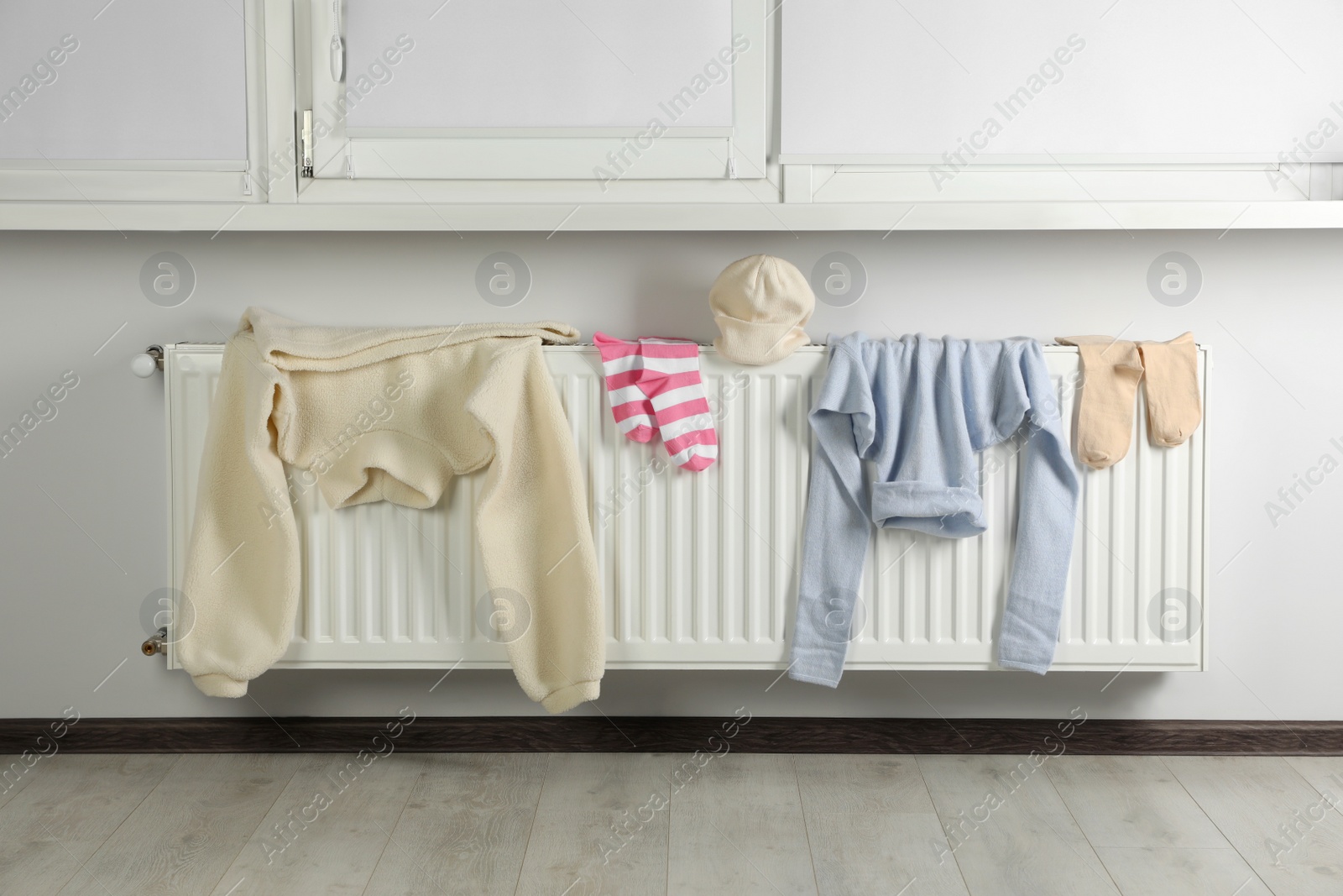 Photo of Clean clothes on heating radiator near window indoors