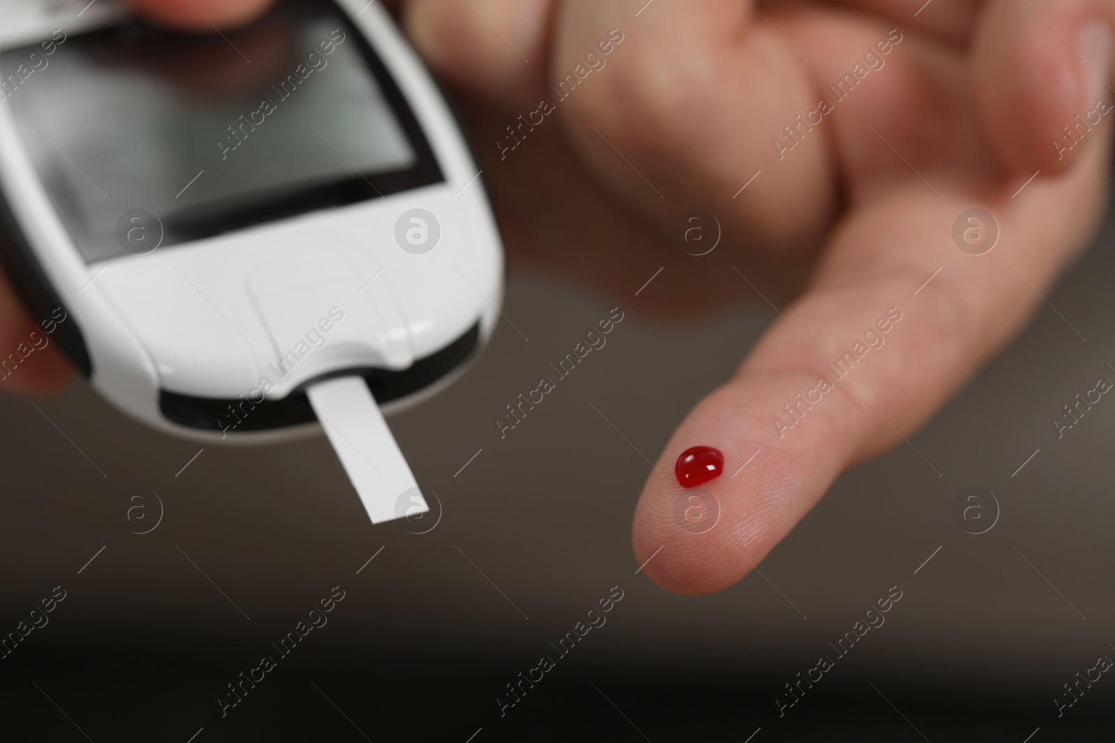Photo of Diabetes test. Man checking blood sugar level with glucometer on blurred background, closeup