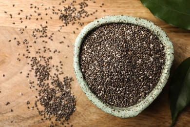 Bowl with chia seeds on wooden table, flat lay