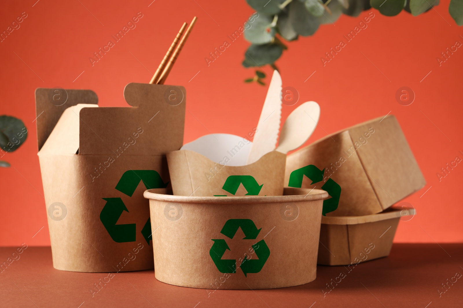 Image of Set of eco friendly food packaging with recycling symbols on coral background