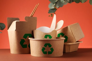 Image of Set of eco friendly food packaging with recycling symbols on coral background