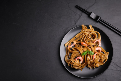 Tasty buckwheat noodles with shrimps on black table, flat lay. Space for text