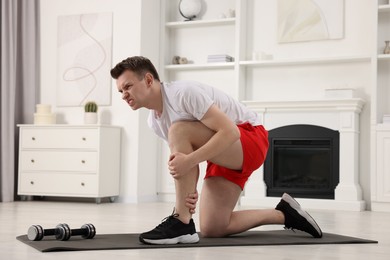 Photo of Man suffering from leg pain on mat at home