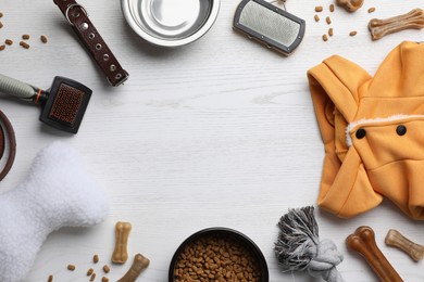 Photo of Flat lay composition with dog clothes, food and accessories on white wooden table. Space for text