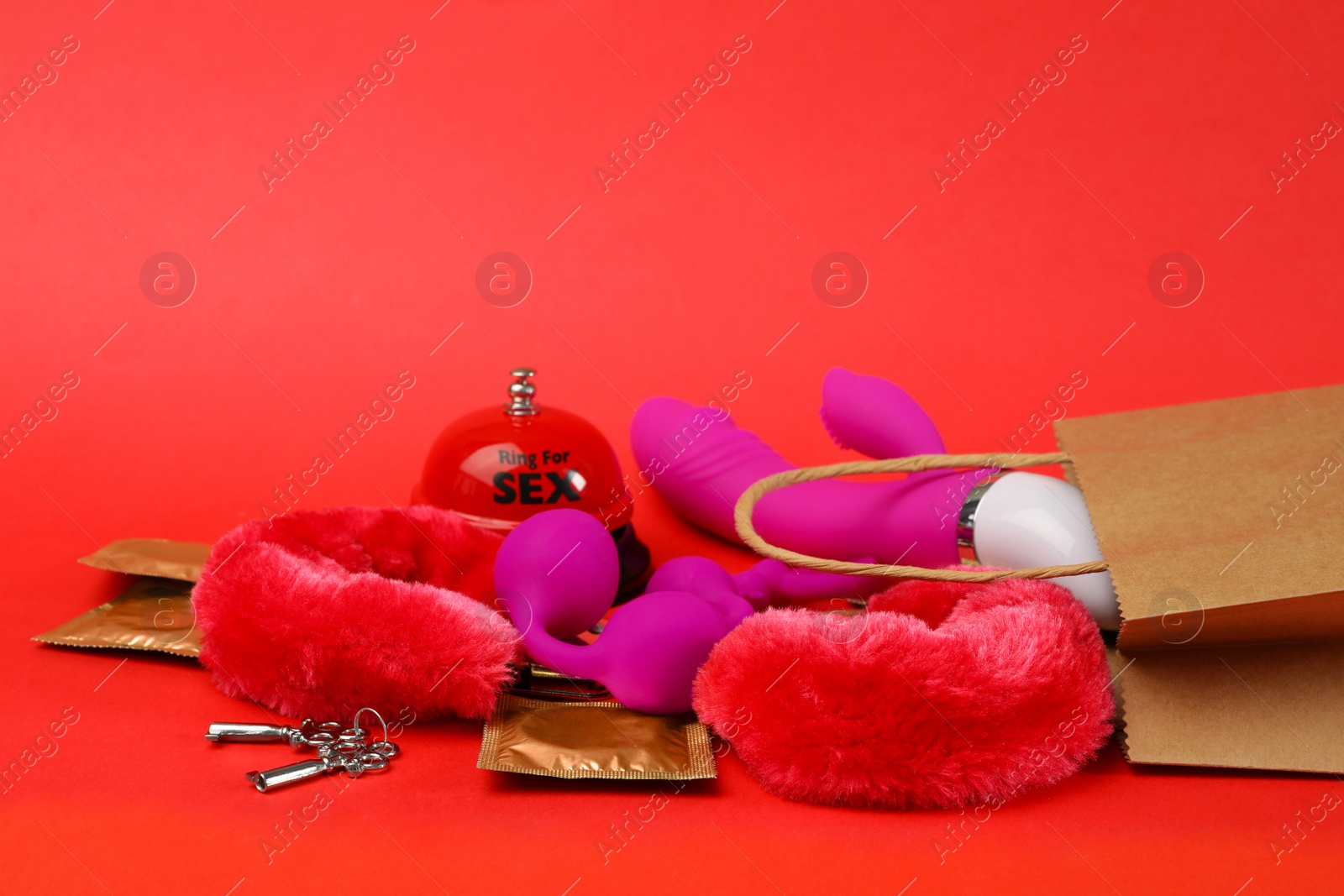 Photo of Shopping bag and different sex toys on red background