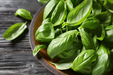 Photo of Fresh green basil on black wooden table, closeup