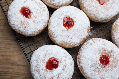 Many delicious donuts with jelly and powdered sugar on wooden table, top view