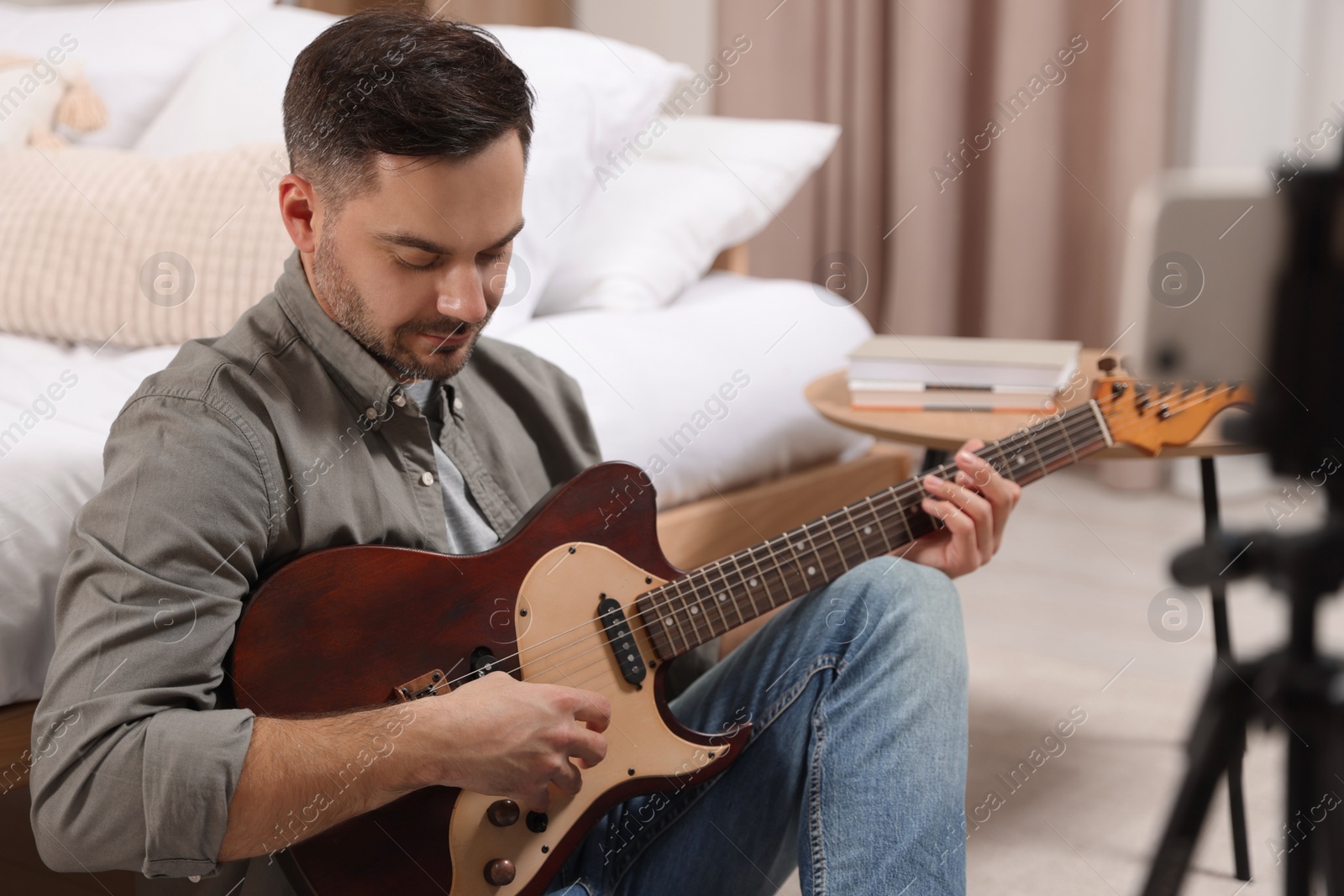 Photo of Music teacher with guitar conducting online lesson at home. Time for hobby