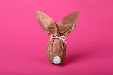 Easter bunny made of kraft paper and egg on pink background