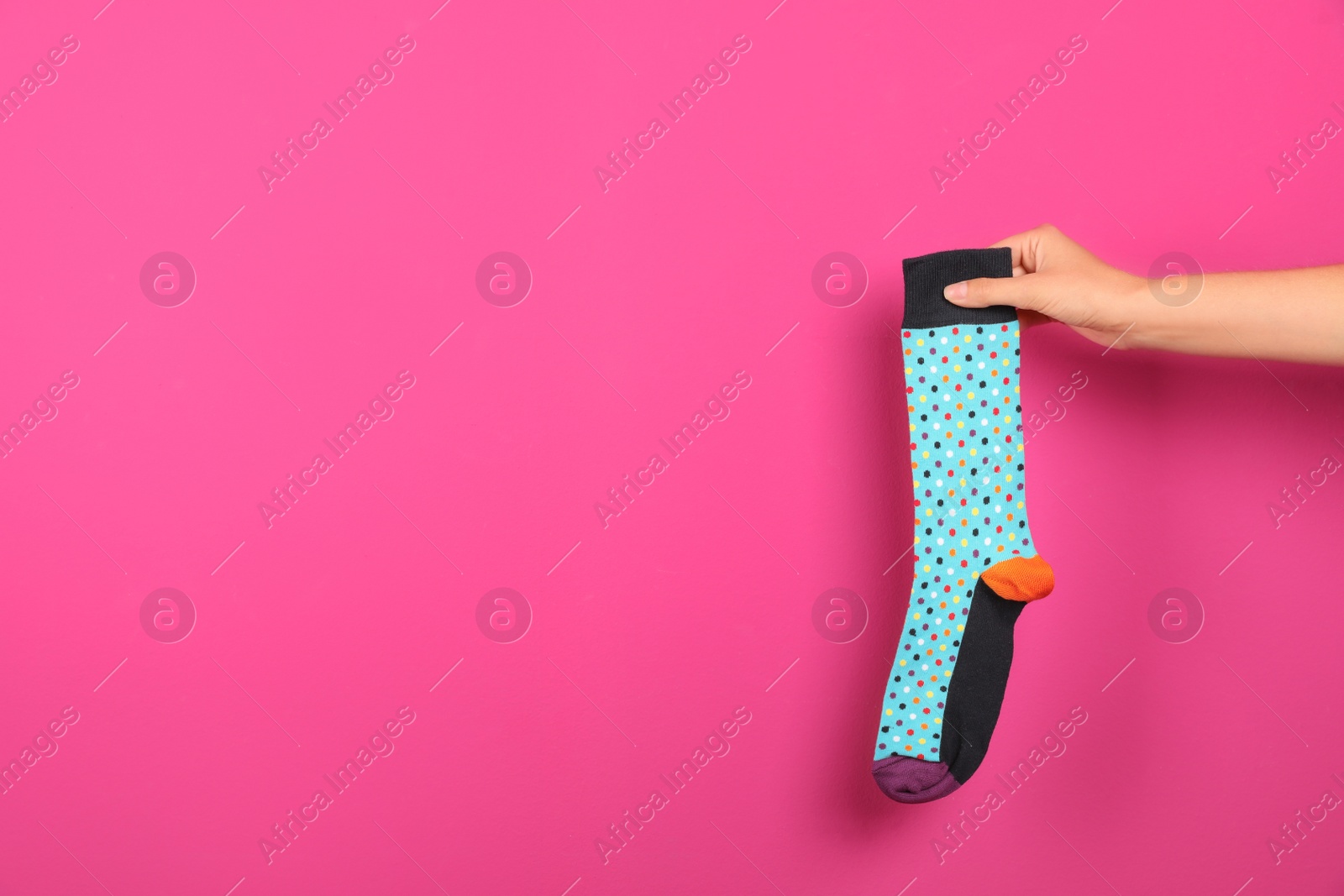 Photo of Woman holding bright sock and space for design on color background