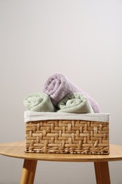 Photo of Clean towels in laundry basket on wooden table against gray background, space for text