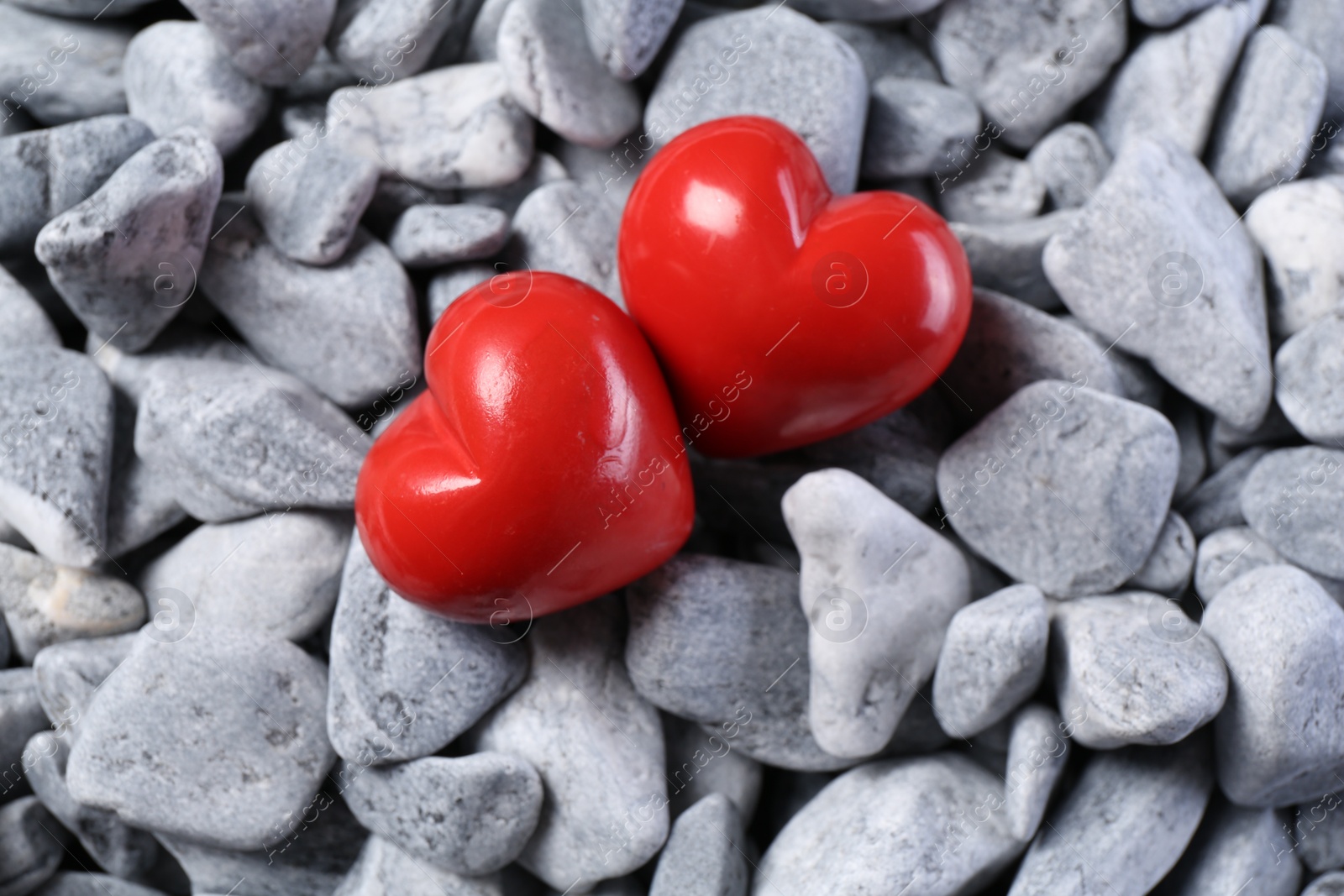 Photo of Red decorative hearts on grey stones, top view