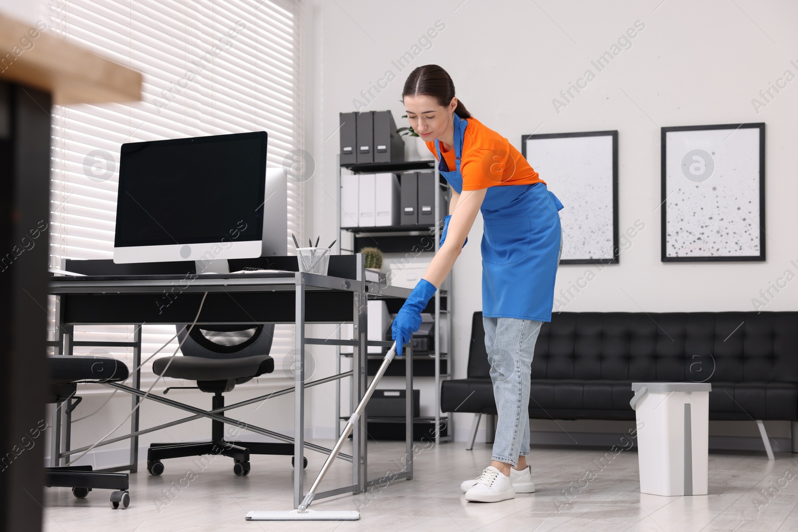 Photo of Cleaning service. Woman washing floor with mop in office