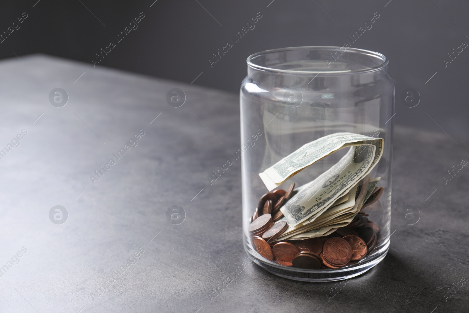 Photo of Donation jar with money on table against grey background. Space for text