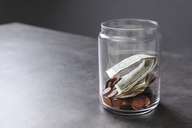 Donation jar with money on table against grey background. Space for text