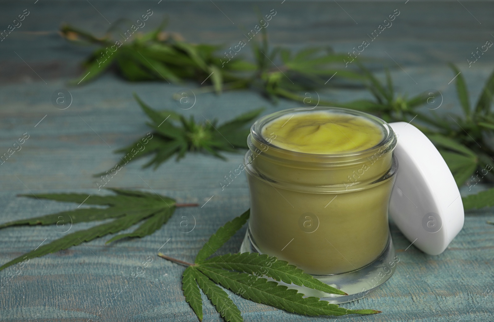 Photo of Jar of hemp cream on blue wooden table, space for text. Organic cosmetics