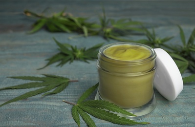 Photo of Jar of hemp cream on blue wooden table, space for text. Organic cosmetics