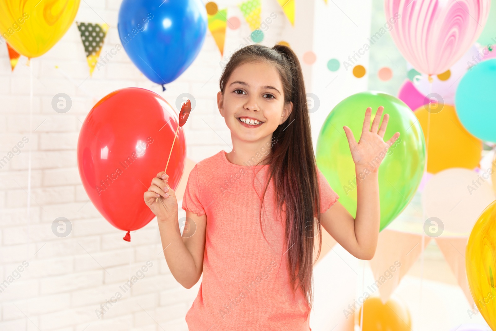 Photo of Happy girl near bright balloons at birthday party indoors