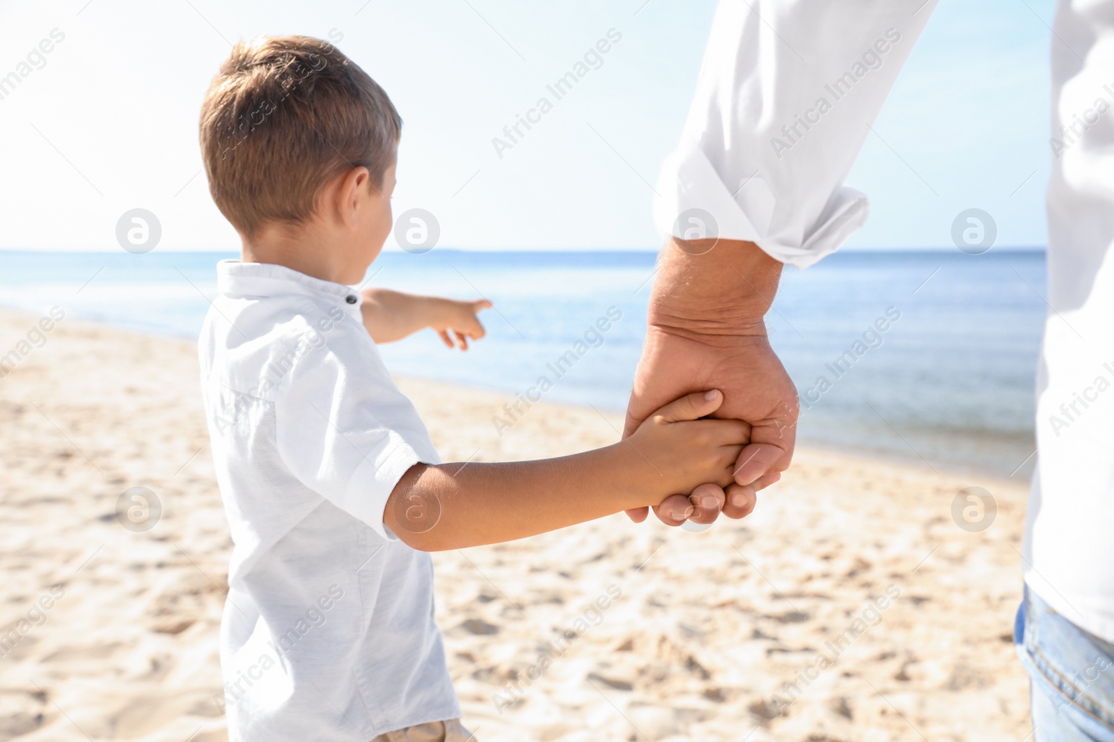 Photo of Little boy with grandfather on sea beach, closeup