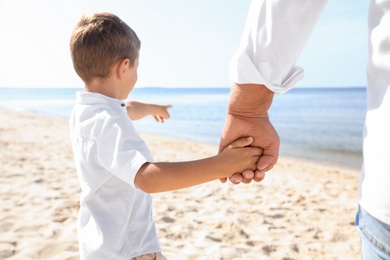 Photo of Little boy with grandfather on sea beach, closeup