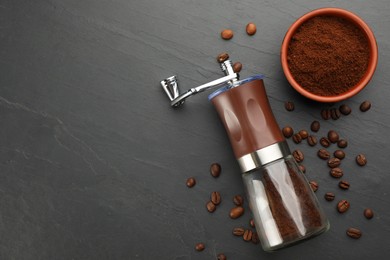 Modern manual coffee grinder with beans and powder on black table, flat lay. Space for text