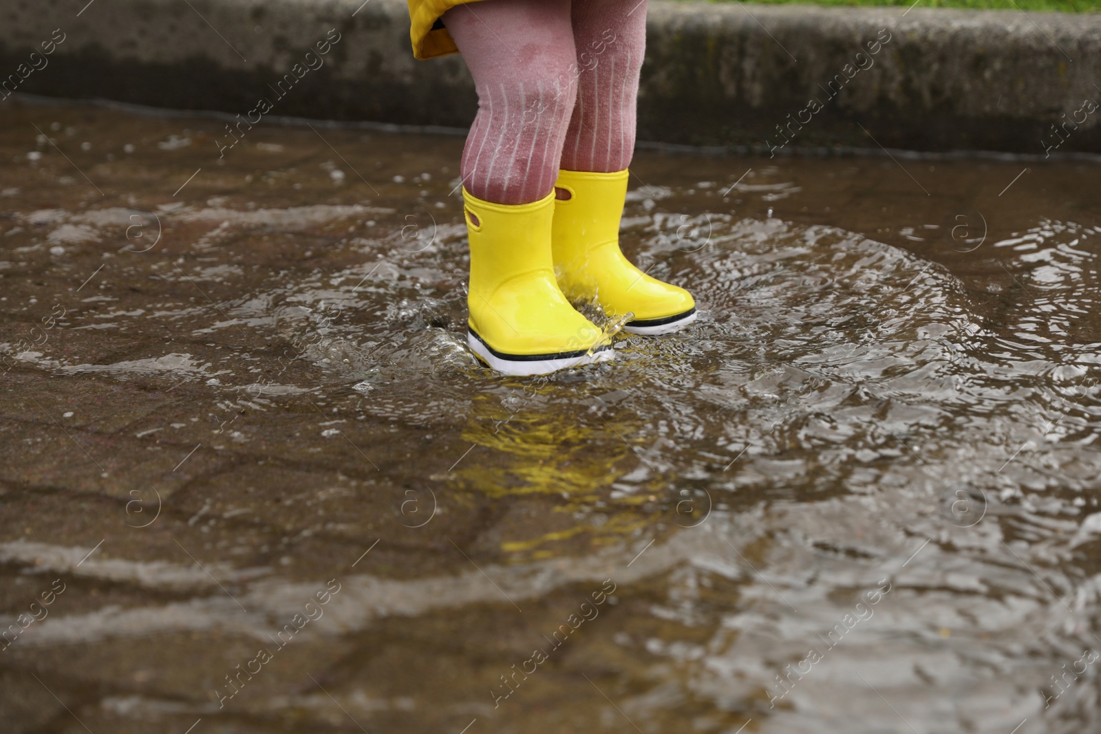 Photo of Girl walking in puddle outdoors on rainy weather, closeup