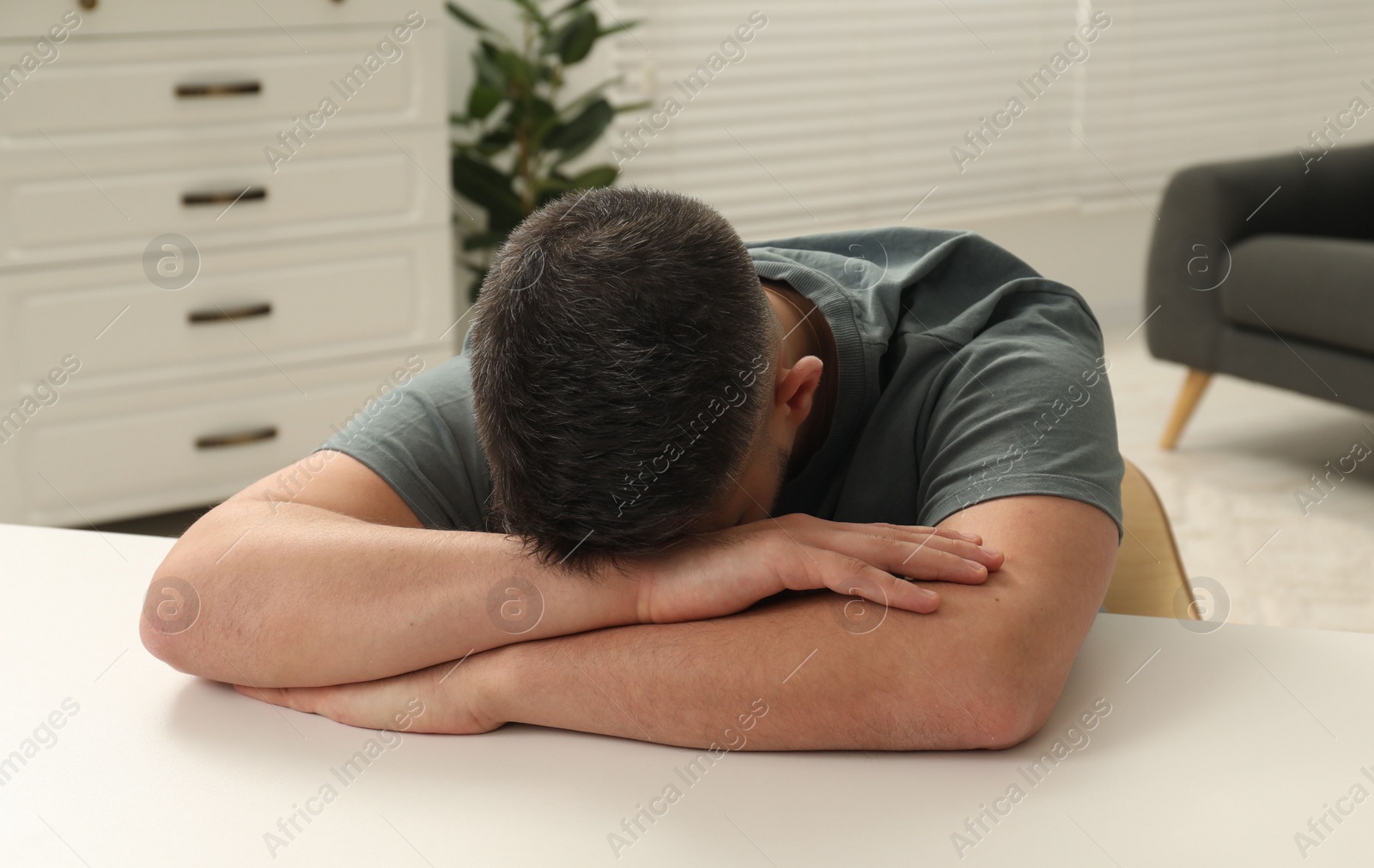 Photo of Sad man lying on table at home