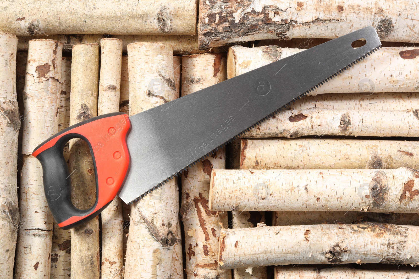 Photo of Saw with colorful handle on firewood, top view