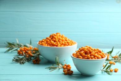 Photo of Fresh ripe sea buckthorn on light blue wooden table. Space for text