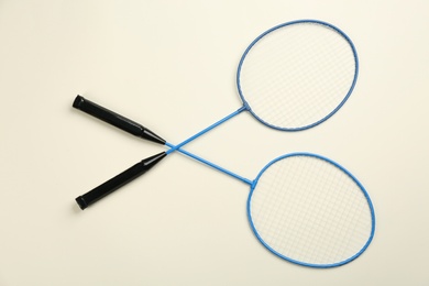 Rackets on beige background, flat lay. Badminton equipment