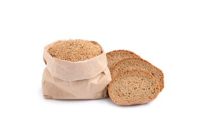 Fresh bread crumbs in paper bag and slices of loaf on white background