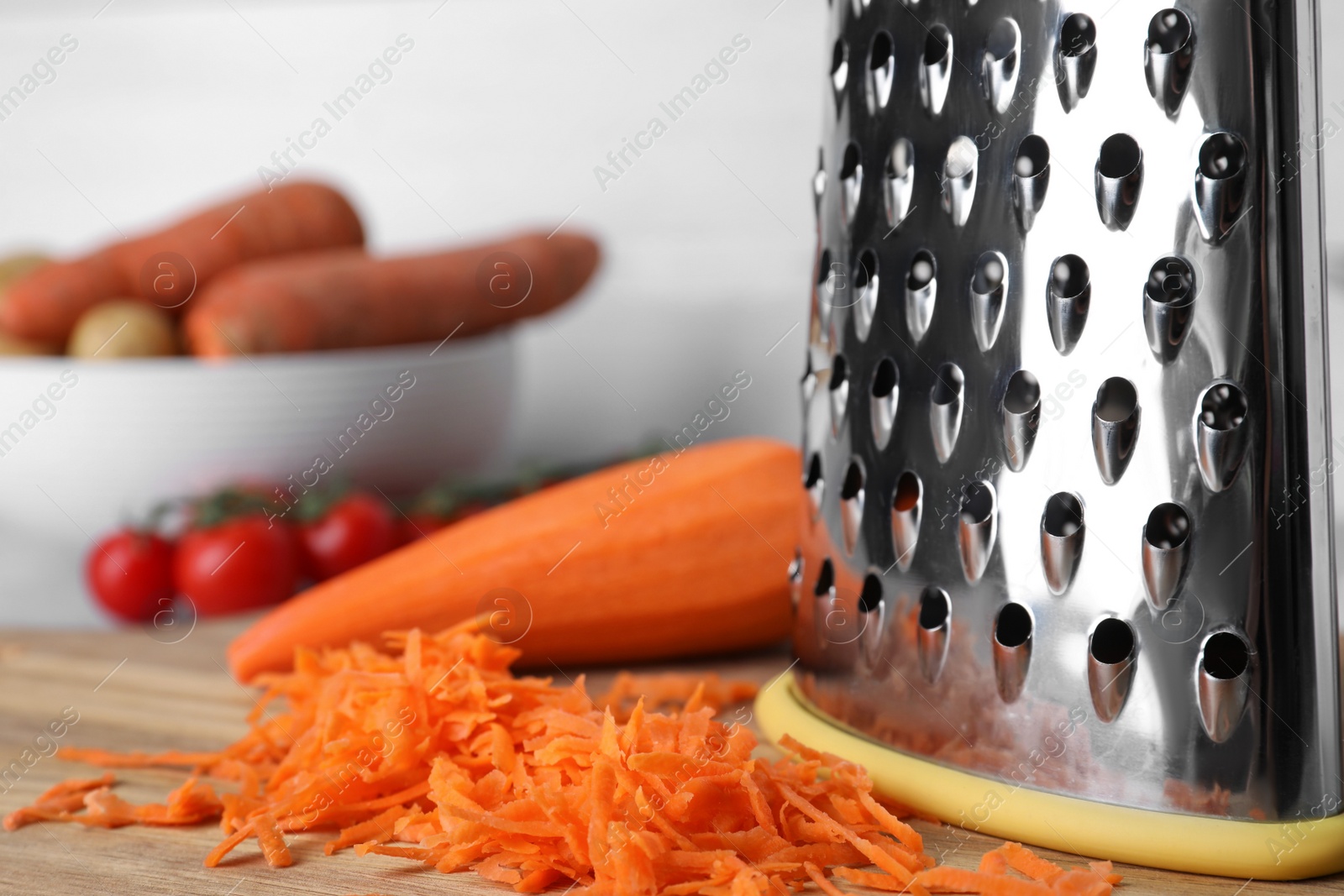 Photo of Grater and fresh ripe carrot on wooden board, closeup