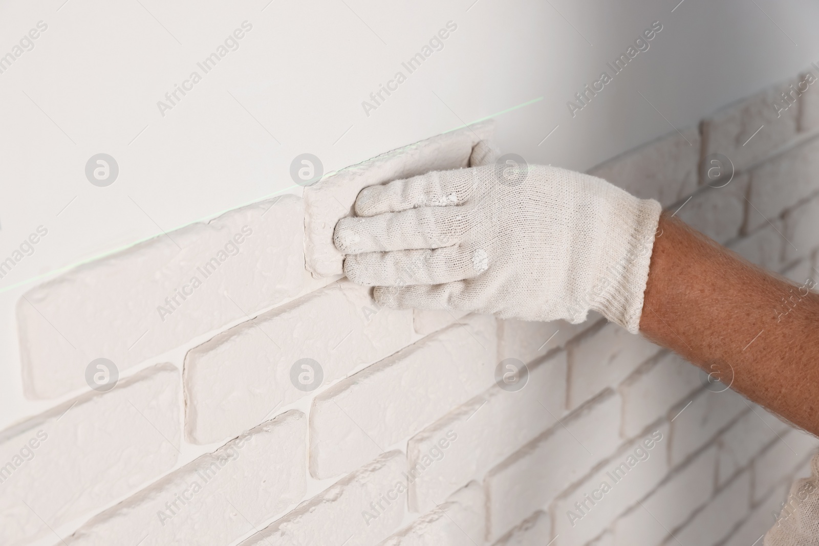 Photo of Worker installing decorative wall tiles in room, closeup