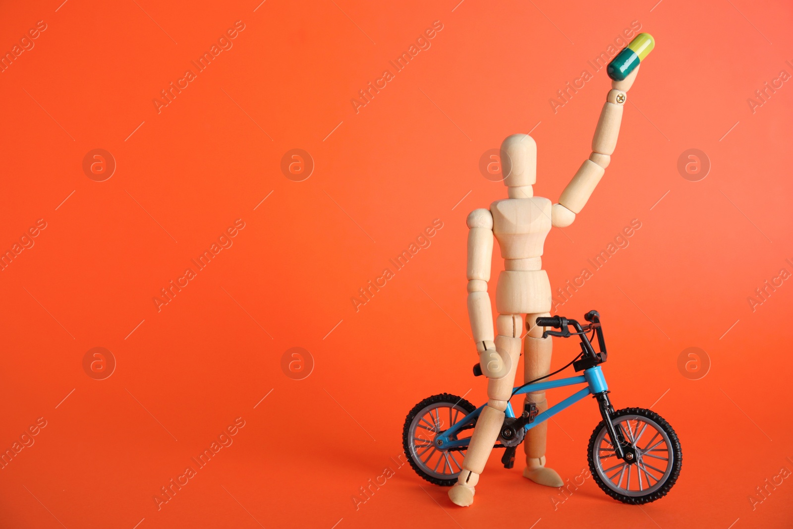 Photo of Sportsman with pill and bike model on red background, space for text. Using doping in cycling sport concept