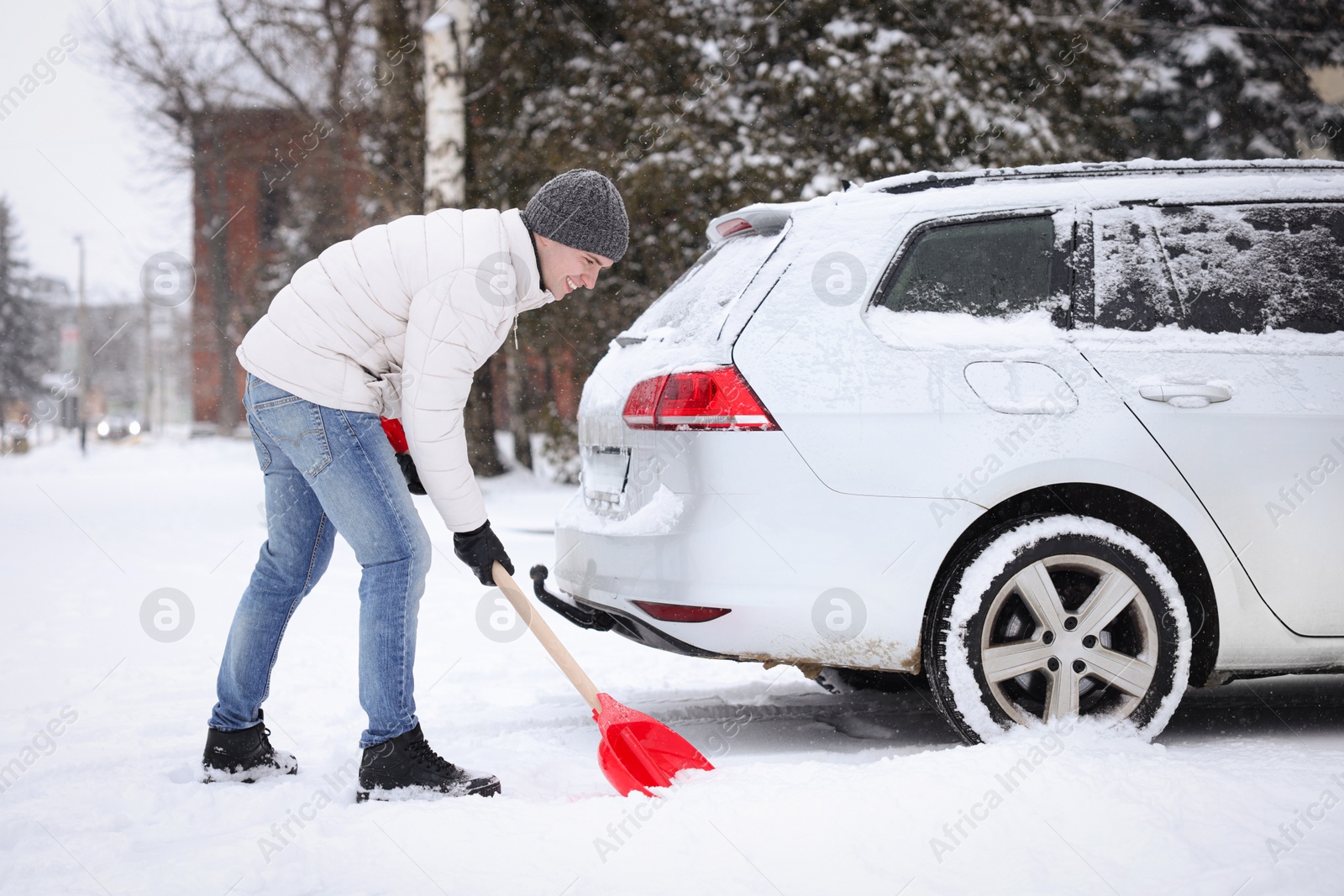 Photo of Man removing snow with shovel near car outdoors