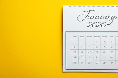 Photo of January 2020 calendar on yellow background, top view. Space for text
