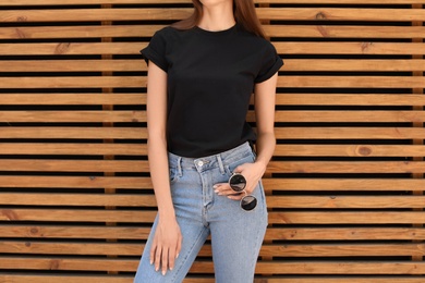 Young woman wearing black t-shirt against wooden wall on street. Urban style