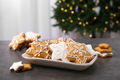 Photo of Decorated cookies on grey table against blurred Christmas lights