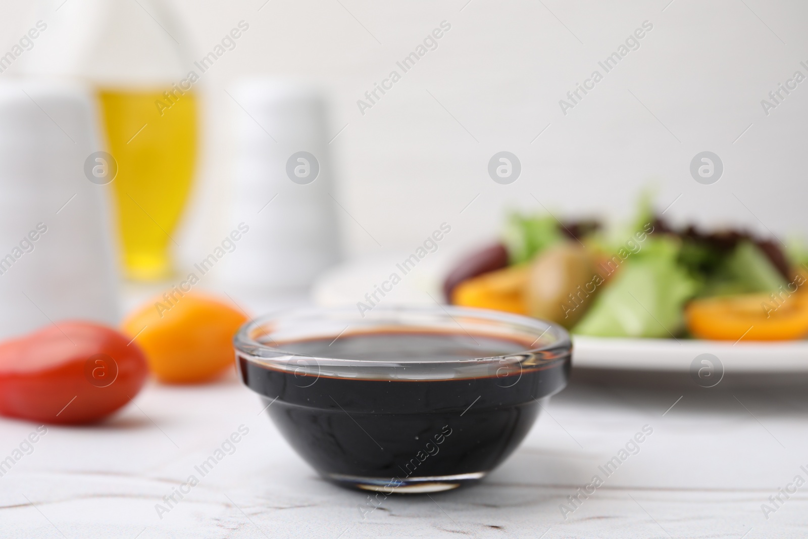 Photo of Vinegar in bowl on light textured table, closeup