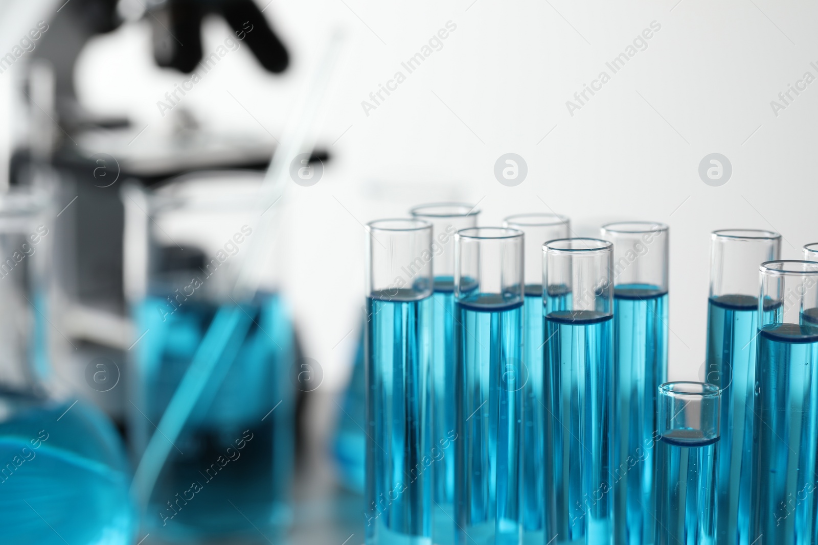 Photo of Test tubes with light blue liquid in laboratory, closeup. Space for text